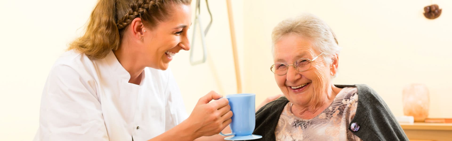 caregiver giving cup of water to elderly