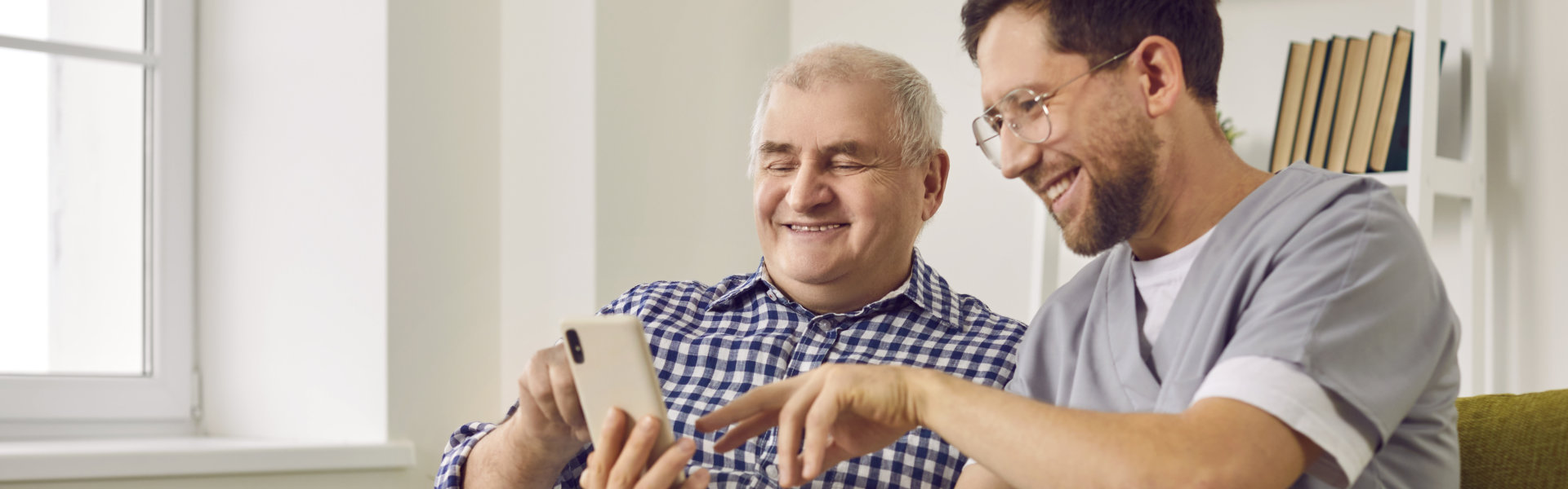 caregiver and elderly using a phone